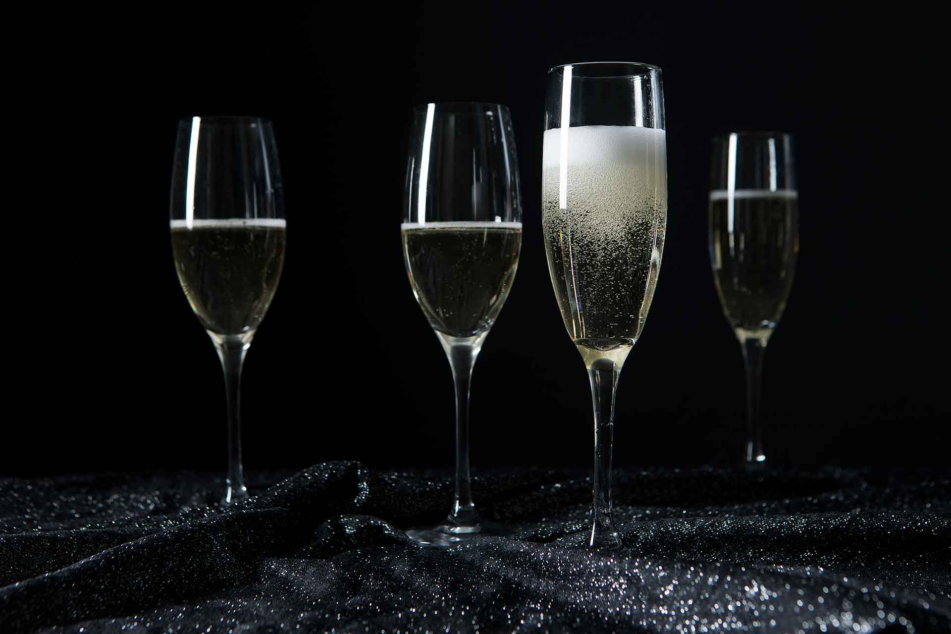 Four champagne glasses in a dark room