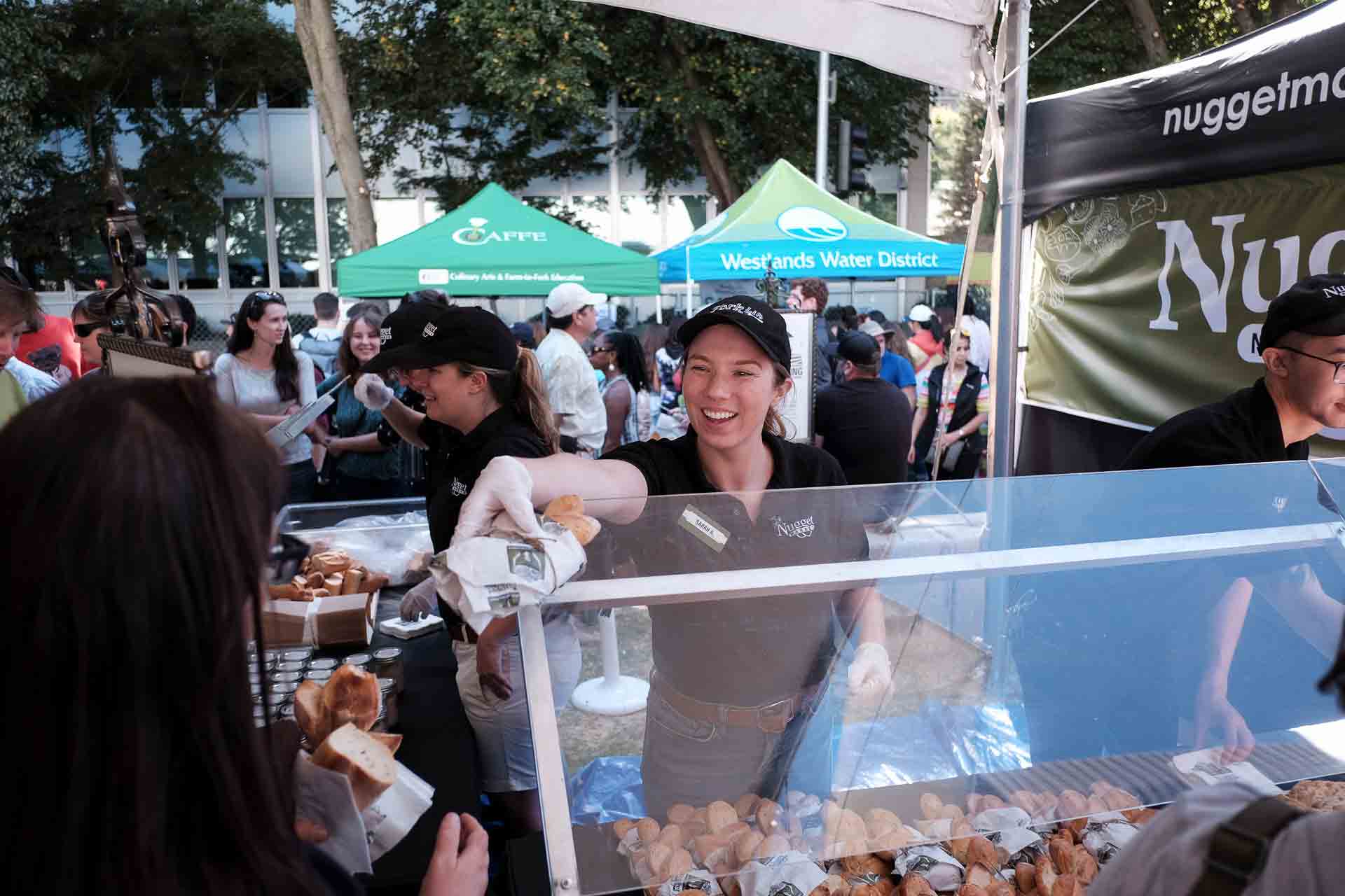 Nugget Markets kitchen associates passing a sandwich to a guest